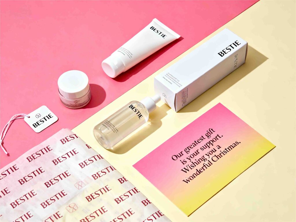Custom skincare Christmas packaging with printed tissue paper, branded gift box, hang tag, and festive holiday card for BESTIE beauty brand.
