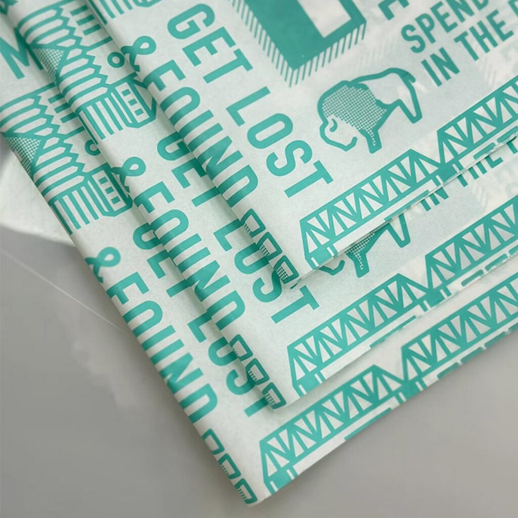 Custom printed tissue paper with turquoise graphics and text, showcasing branded eco-friendly packaging design for retail and e-commerce products.